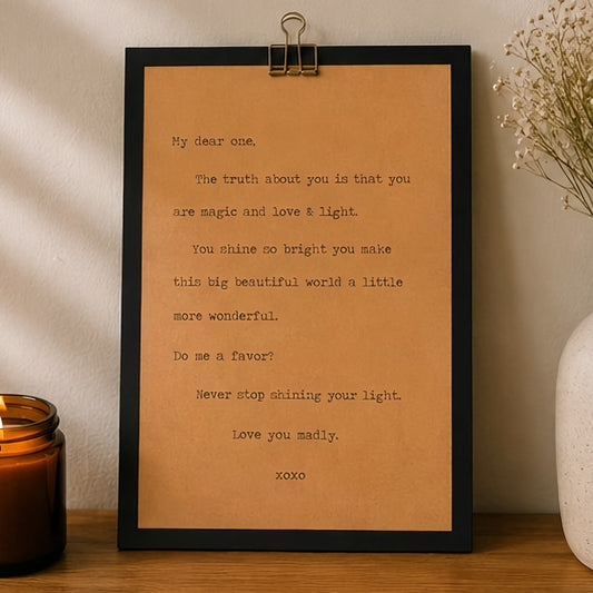 Inspirational wood sign featuring a heartfelt never stop shining your light message styled beside an amber candle and neutral decor