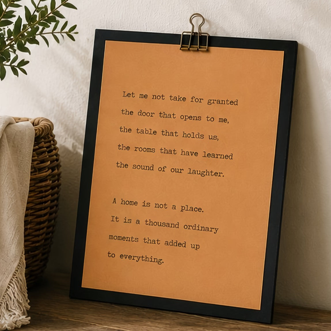 Minimal home quote wood sign with black border and kraft paper design styled with greenery and woven basket decor