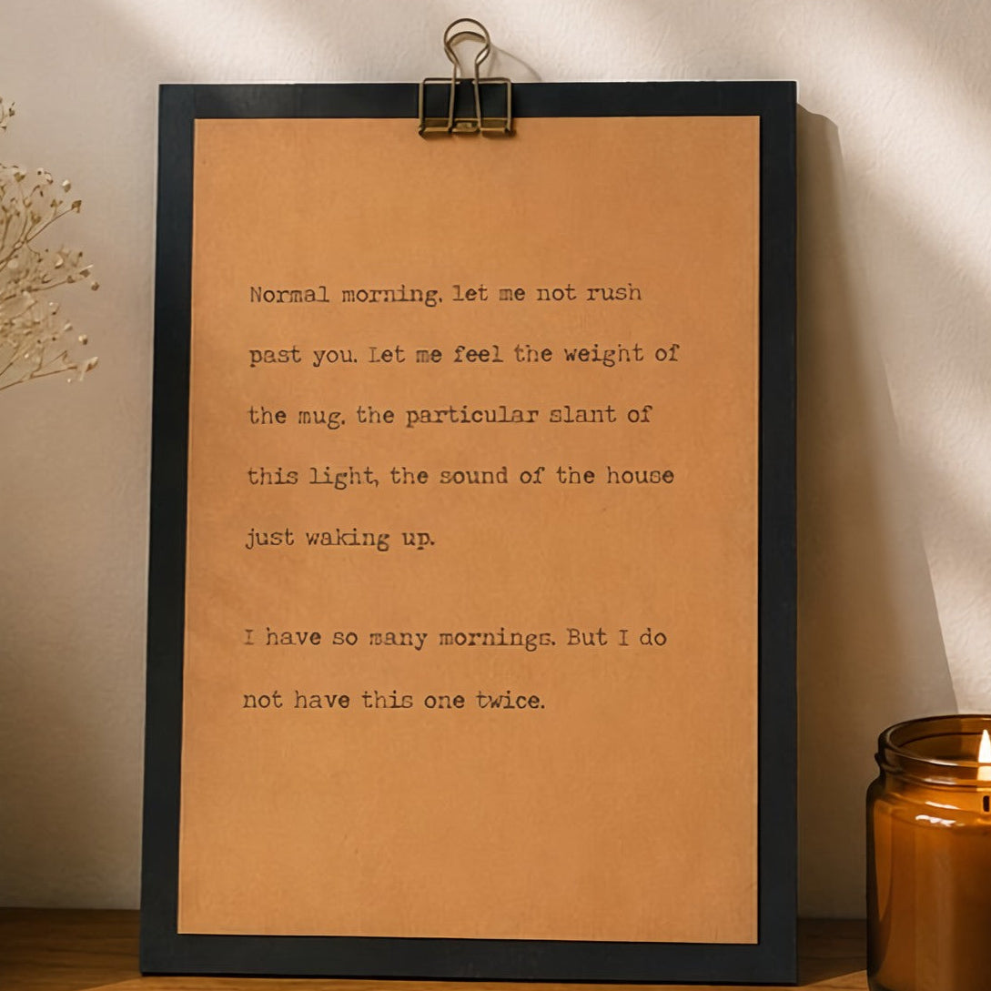 Minimal inspirational wood sign featuring a quote about slowing down and noticing the morning, displayed beside an amber candle