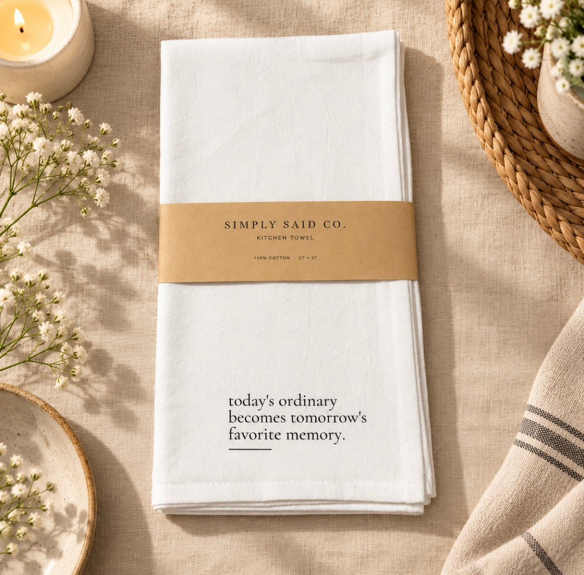 White cotton kitchen towel with quote styled on a soft neutral fabric background