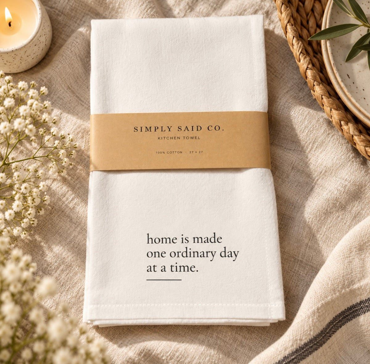 White cotton Home Is Made kitchen towel styled with neutral linens and candle